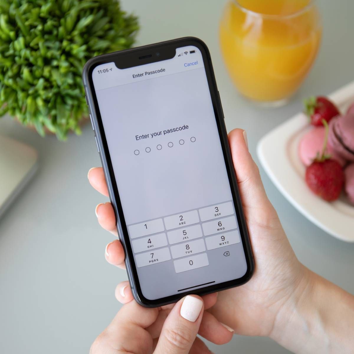 Woman holding an iPhone 11 with the Enter your passcode prompt on the screen.