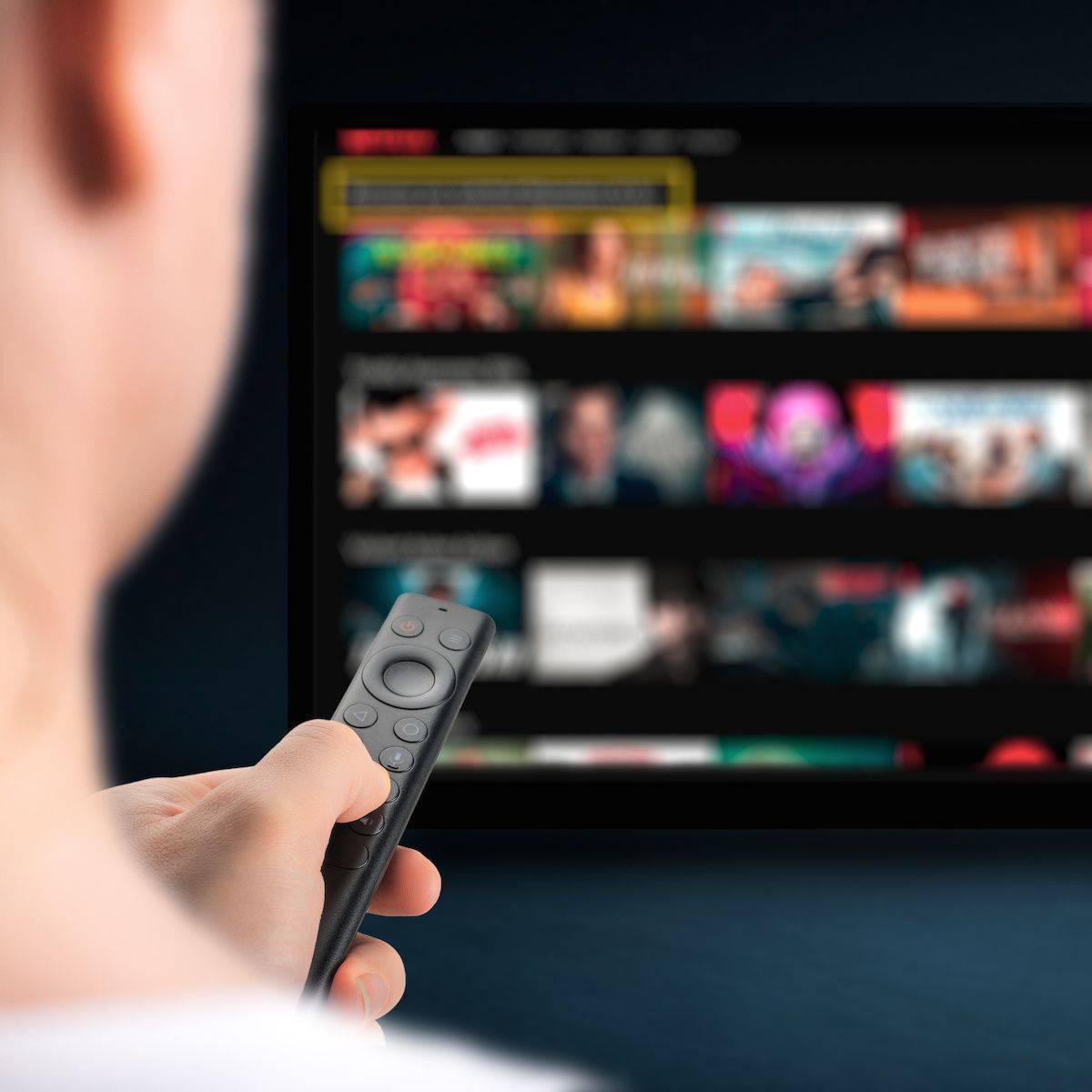 A person points a remote at a smart TV and chooses a streaming show or movie to watch.