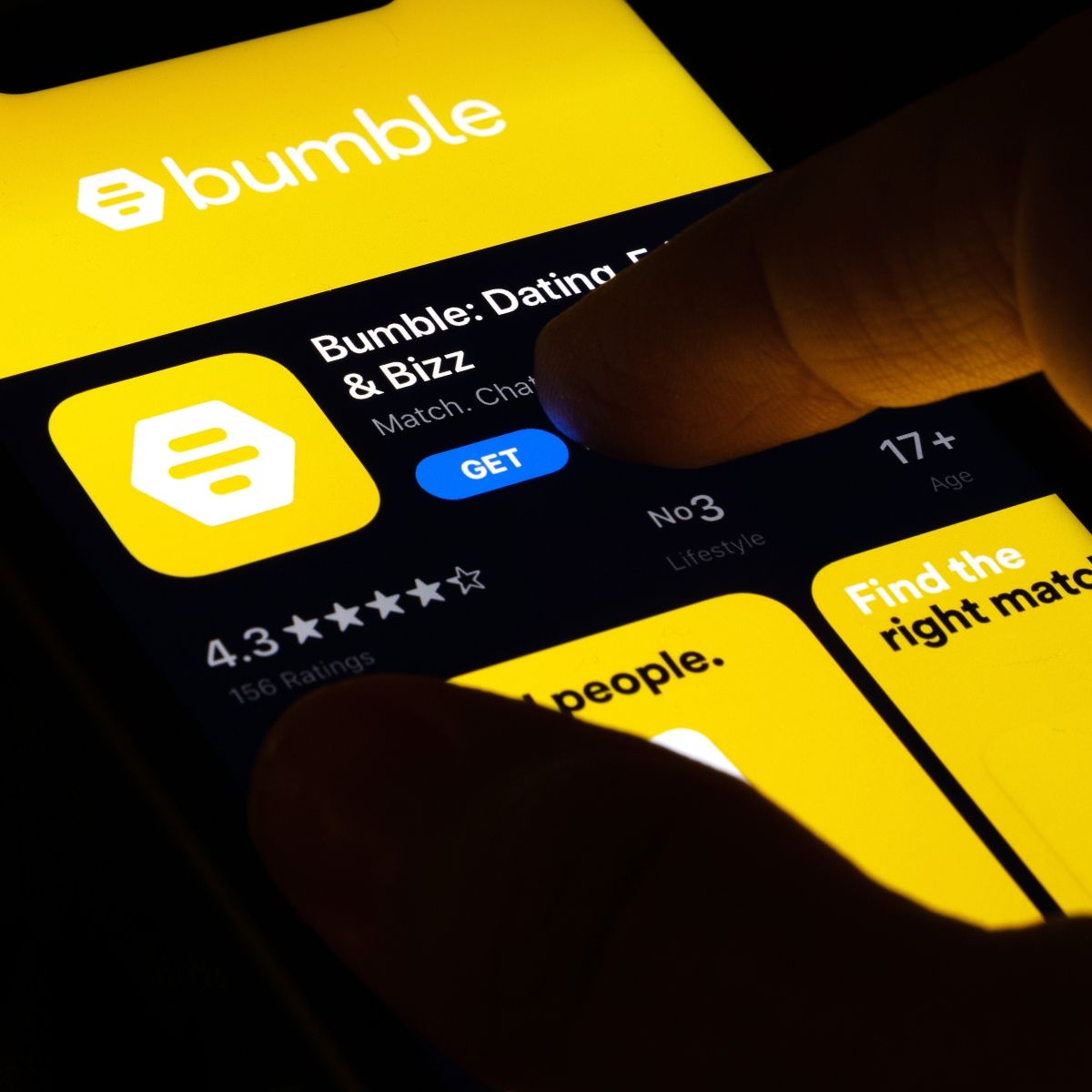 Phone screen with dating app Bumble in yellow and finger about to press the button get