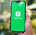 Holding cellphone with green Cash App on the screen