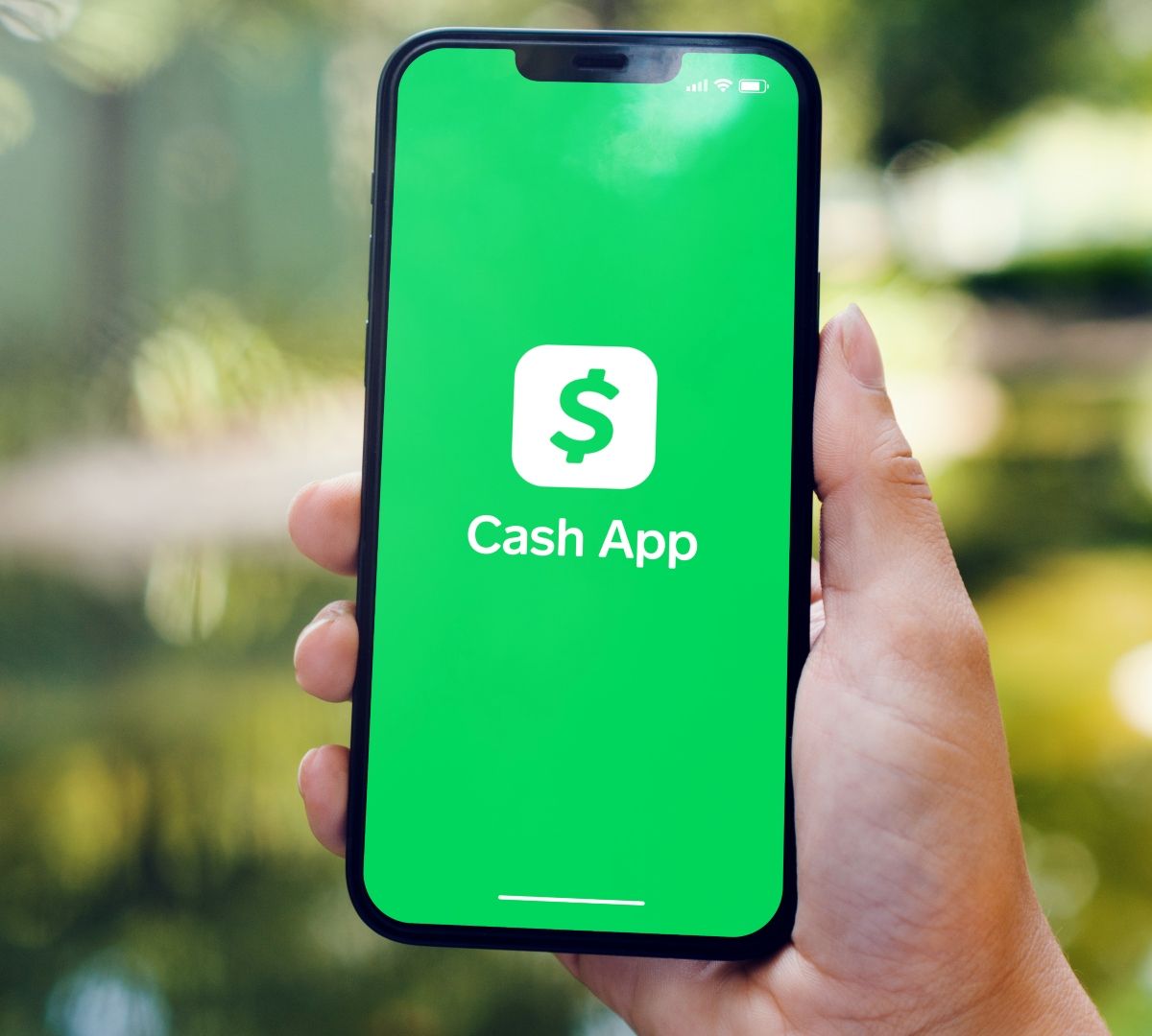 Holding cellphone with green Cash App on the screen