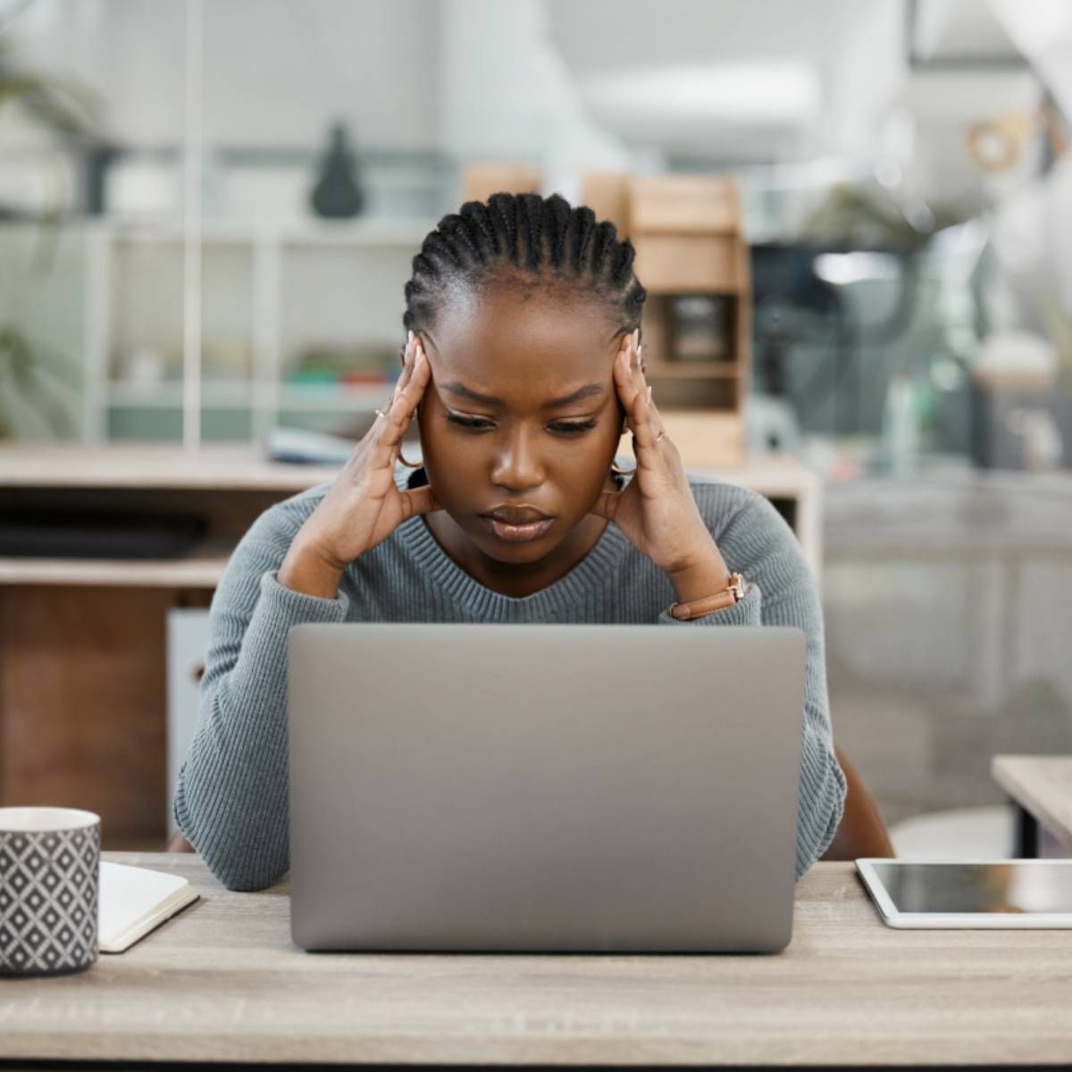 A woman working on her laptop and looking stressed out.