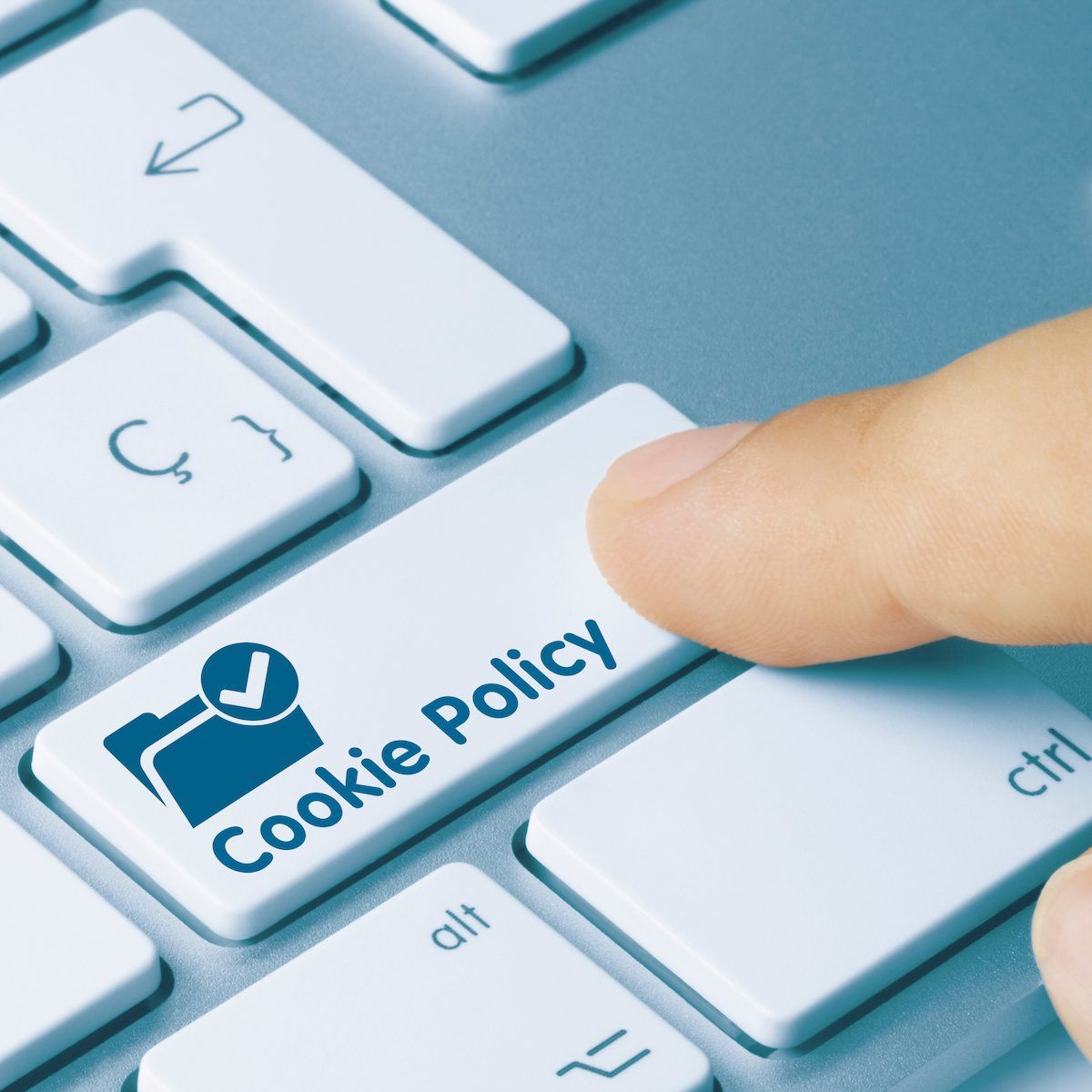 A finger shown pressing a button on a keyboard that says &quot;Cookie Policy.&quot;