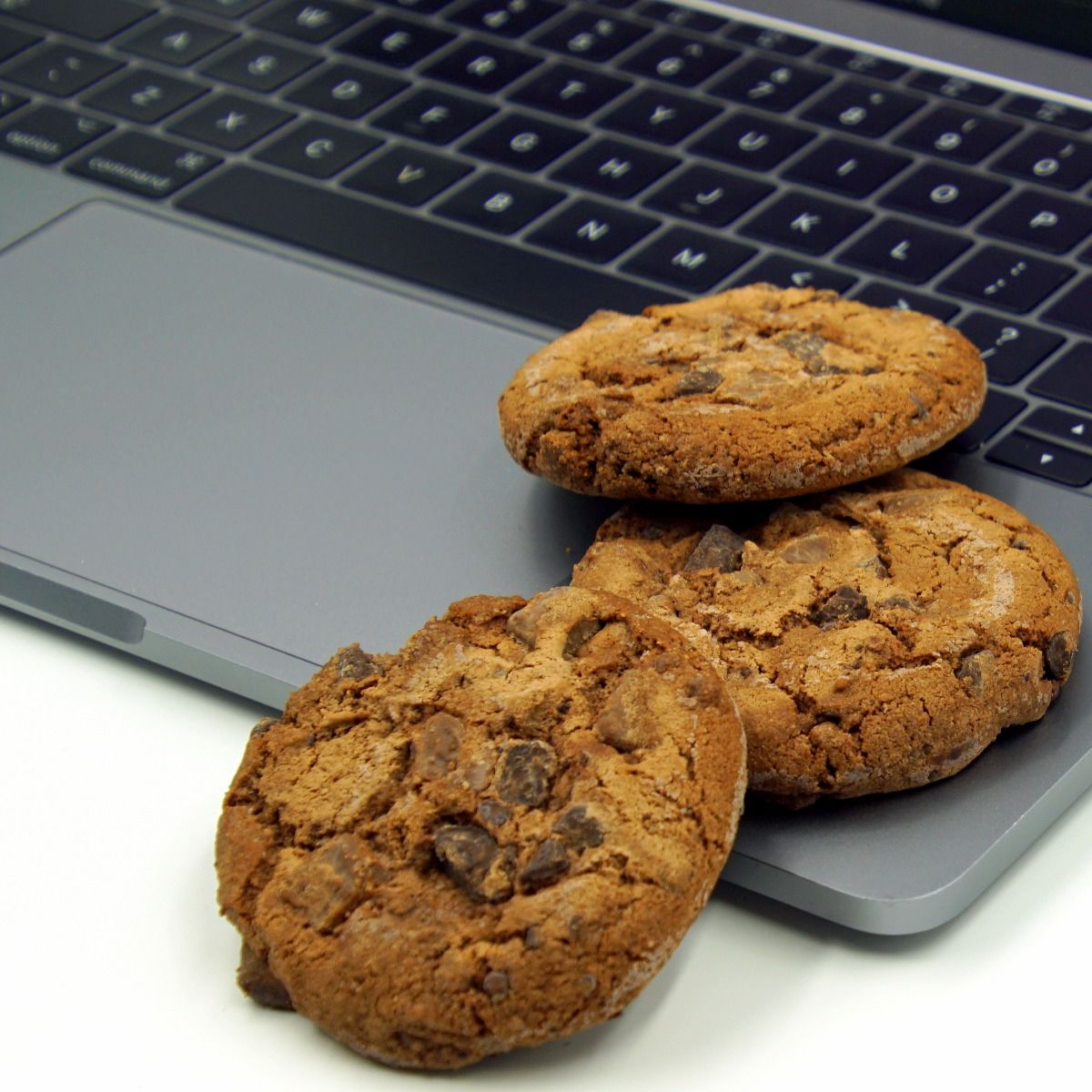 chocolate chip cookies sitting on a laptop keyboard