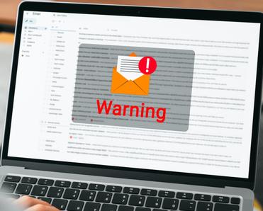 Laptop with email page open and a big envelope with mail warning sign on the screen