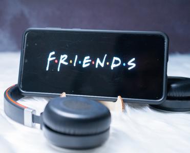Cellphone with FRIENDS tv show logo on screen and headphones 