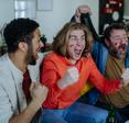 three man with German flag paint on their faces cheering for soccer game