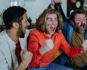 three man with German flag paint on their faces cheering for soccer game