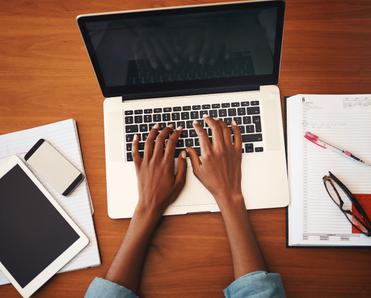 hands typing on laptop aerial view