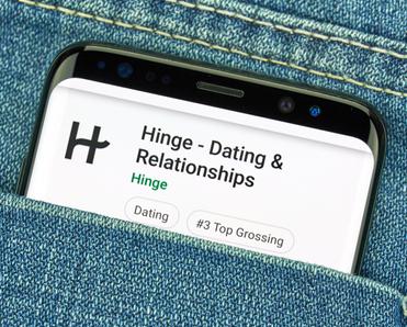 Phone in jeans pocket with dating app Hinge on the screen