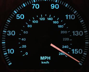 A close-up shot of a lit-up speedometer on a car&#x27;s dashboard. The needle is sitting at just over 150 miles per hour to show fast speeds.