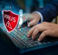 A man&#x27;s hands rest on a laptop keyboard with a red shield and the word &quot;Virus&quot; floating above it to signify the WebHelper virus.