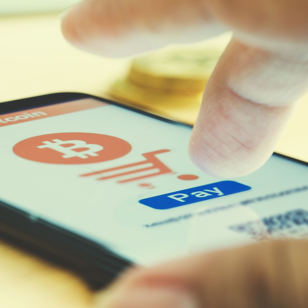 A close-up of a finger tapping a button to pay with bitcoin. Crypto is an anonymous payment method you can use to buy a VPN.