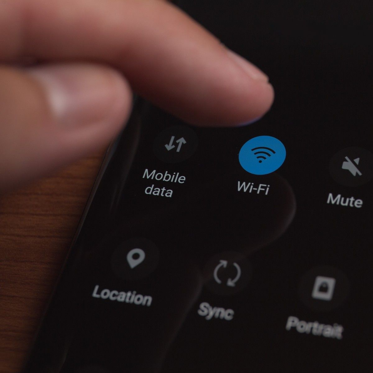 A close-up photo of a man&#x27;s fingers touching the Wi-Fi button on his cell phone.