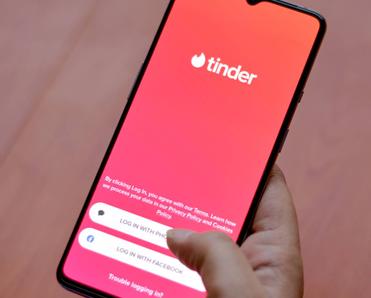 The Tinder app logo on display on a smartphone screen in someone&#x27;s hands.