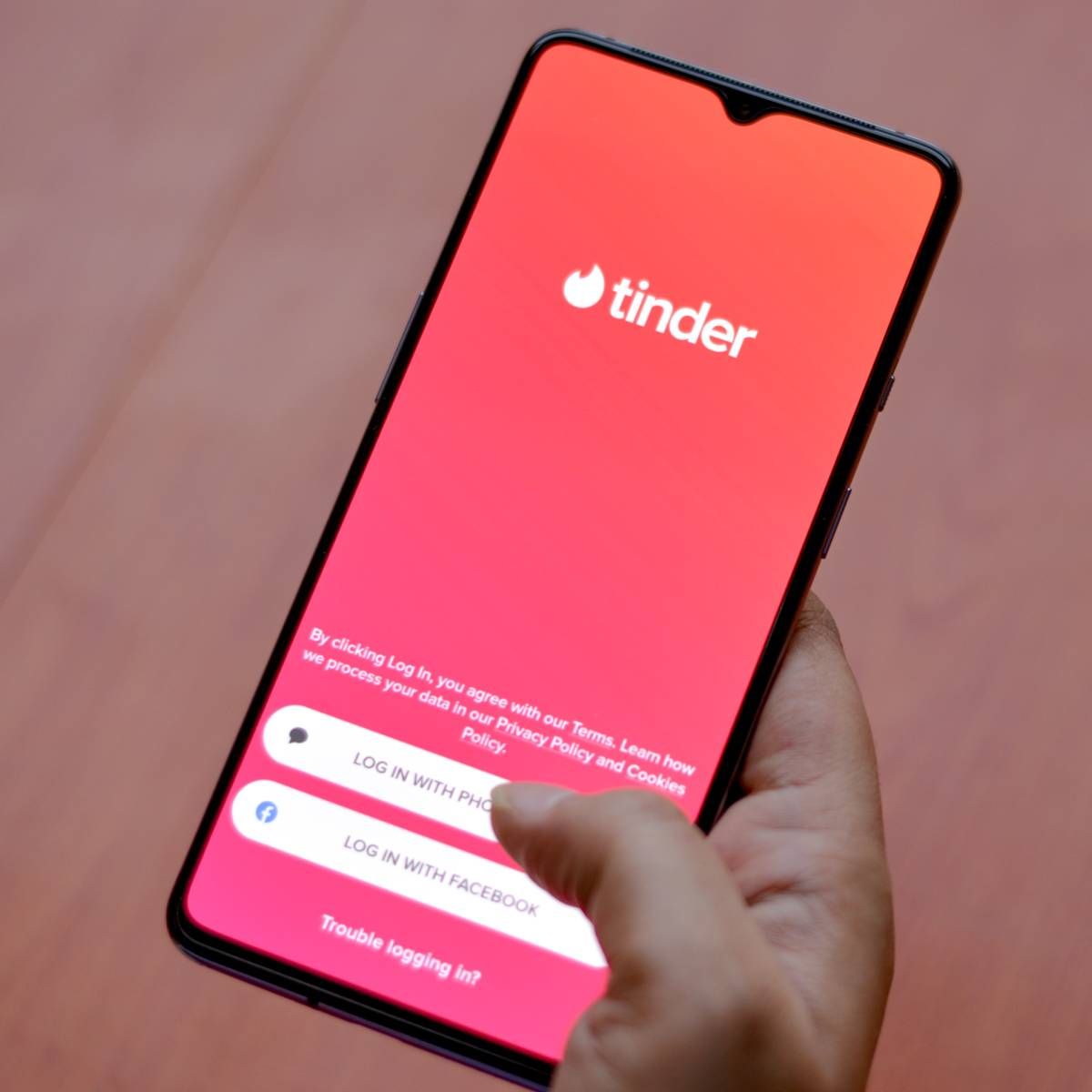 The Tinder app logo on display on a smartphone screen in someone&#x27;s hands.