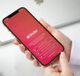 A woman&#x27;s hands holding an iPhone on the Tinder app login screen.