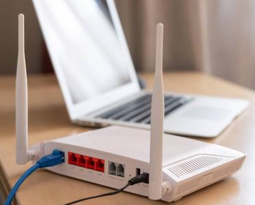 Internet router on working table with blurred laptop in the background.