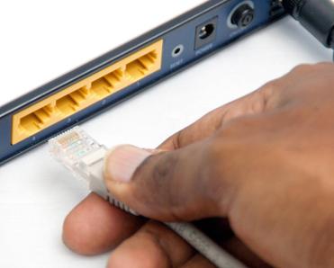 A hand plugging a cable into their modem.