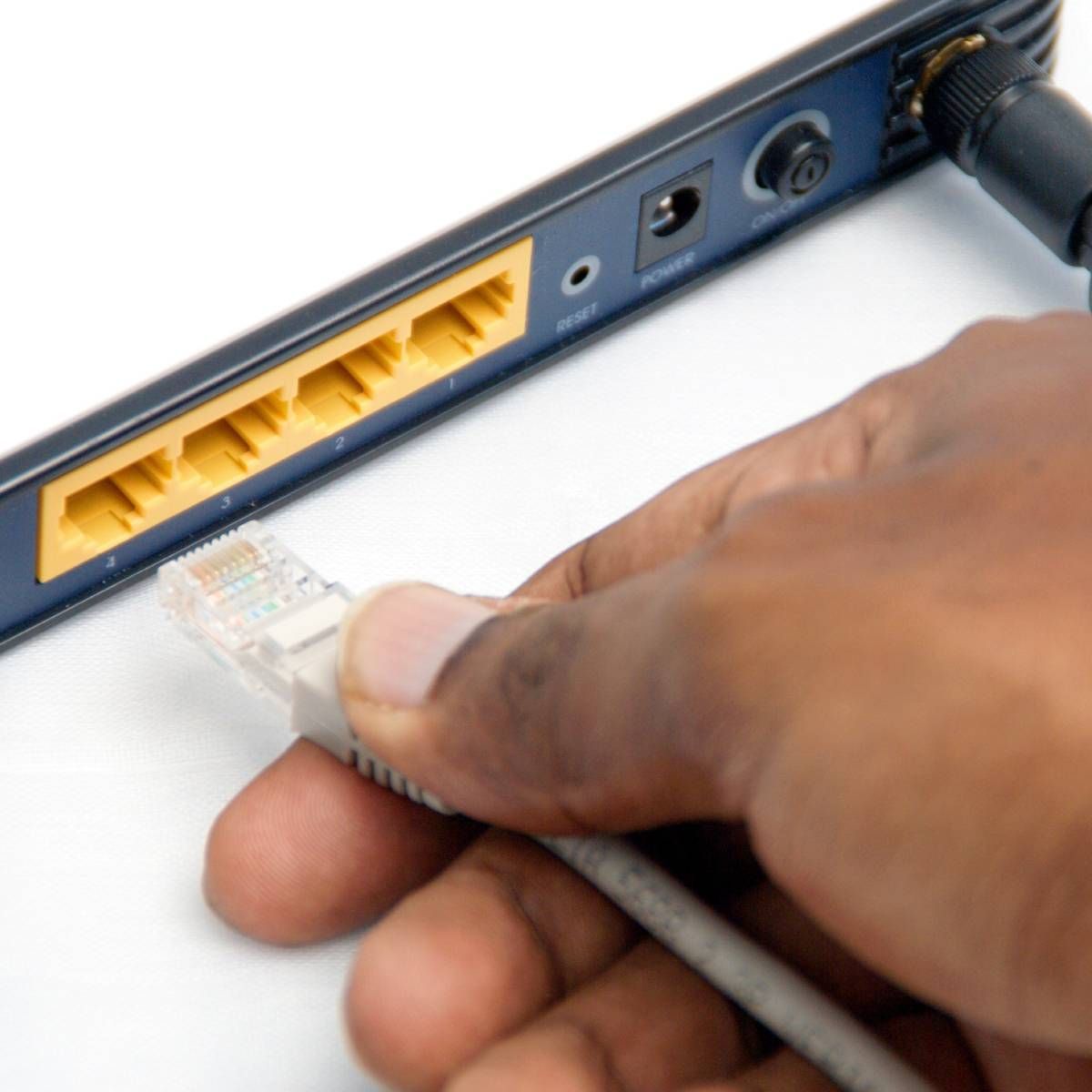 A hand plugging a cable into their modem.