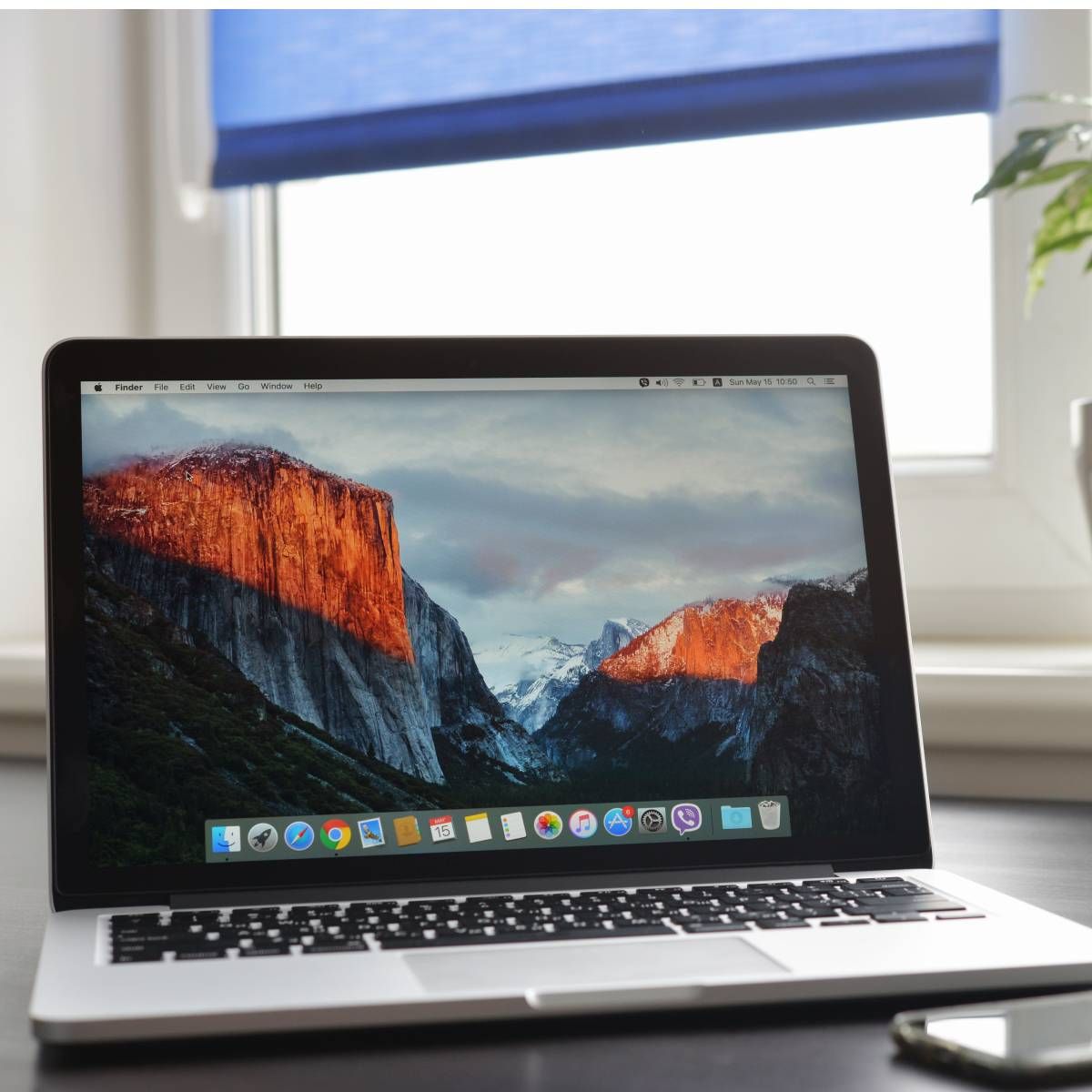 Macbook Pro with retina display on a table along with a smartphone.