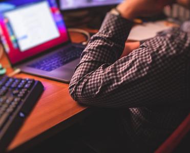 A man in a dress shirt works on his MacBook at home