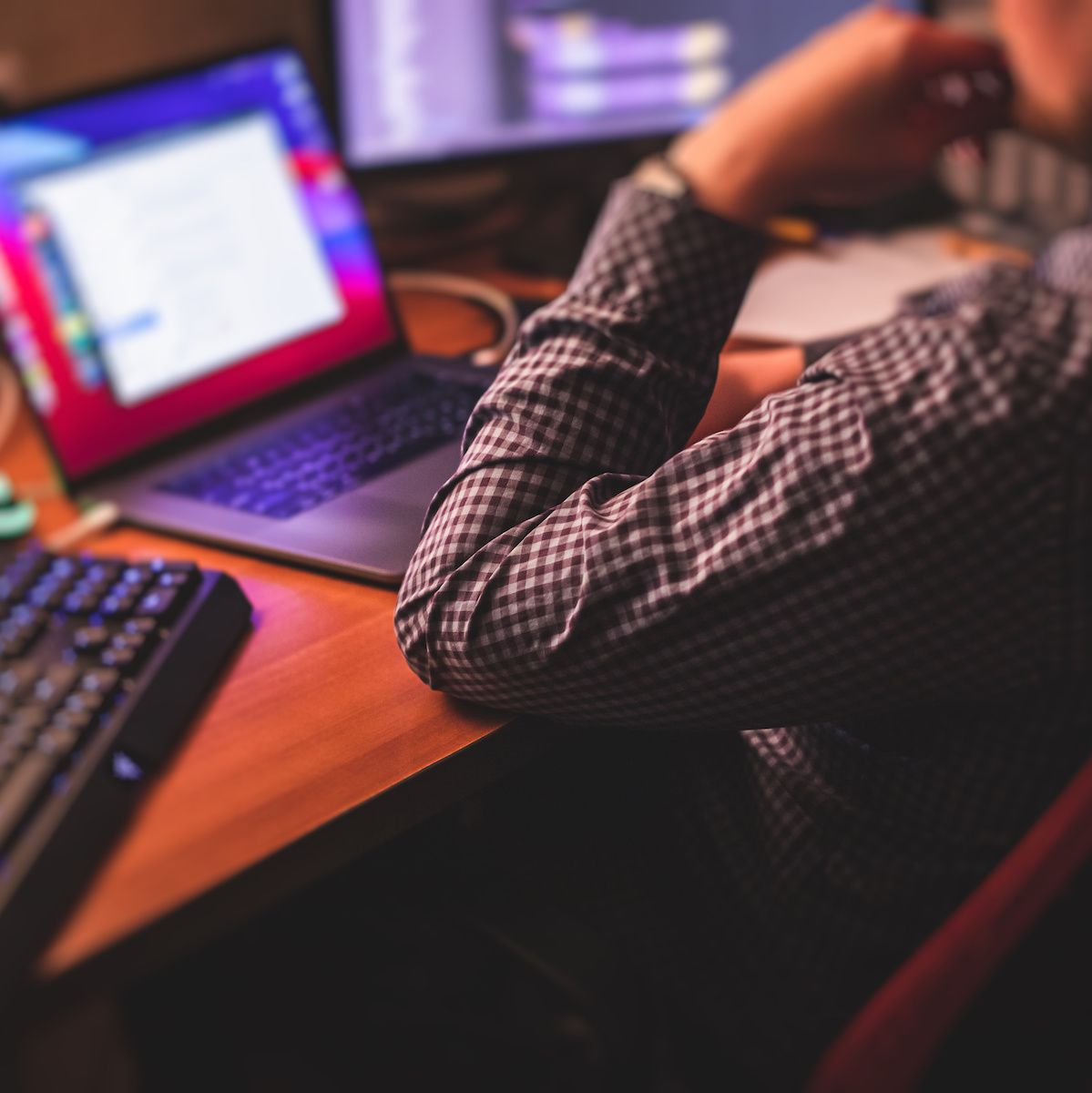 A man in a dress shirt works on his MacBook at home