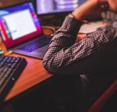 A man in a dress shirt works on his MacBook at home