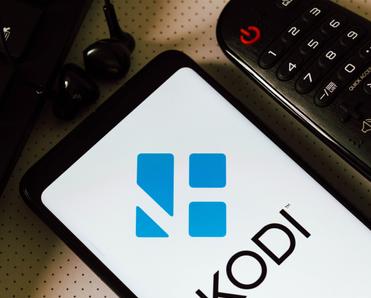 Cellphone screen with logo of Kodi a streaming service next to a remote control 