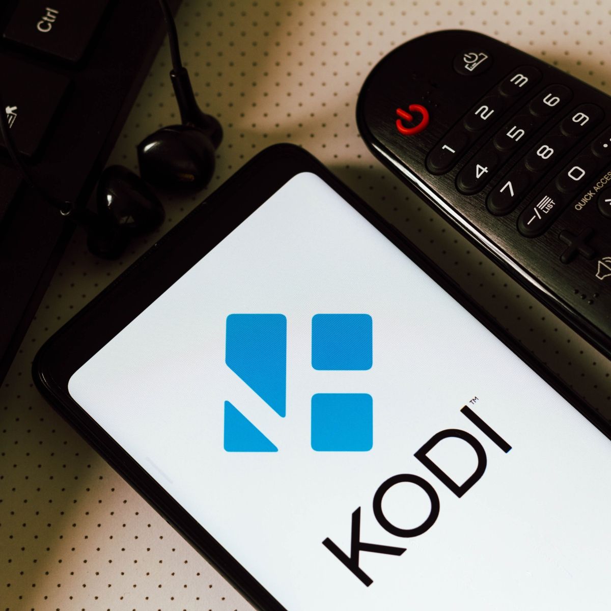 Cellphone screen with logo of Kodi a streaming service next to a remote control 