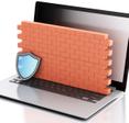 An illustration of an open laptop with a brick wall on top of the keyboard and a shield in front of the wall to illustrate a computer firewall