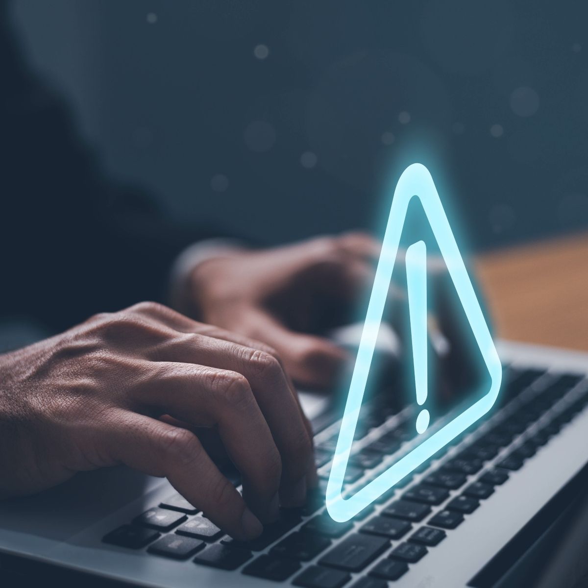 man&#x27;s hands typing on laptop keyboard and a triangle exclamation warning sign floating above