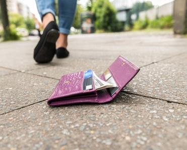 Close-up of wallet on the ground and someone walking away.