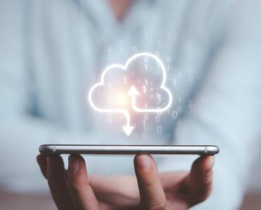 A man balances his cell phone on his fingertips while a download icon (a cloud outline with an arrow pointing down toward the phone) floats above it