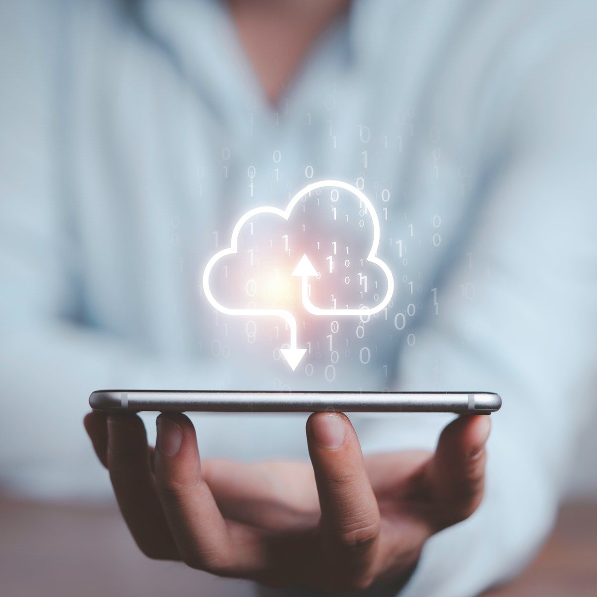 A man balances his cell phone on his fingertips while a download icon (a cloud outline with an arrow pointing down toward the phone) floats above it