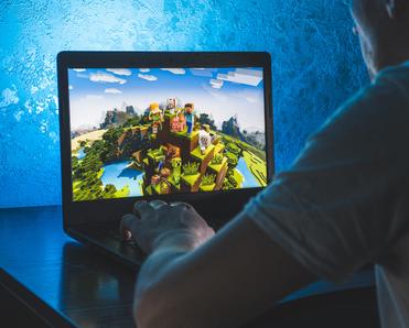 man playing Minecraft on his laptop computer