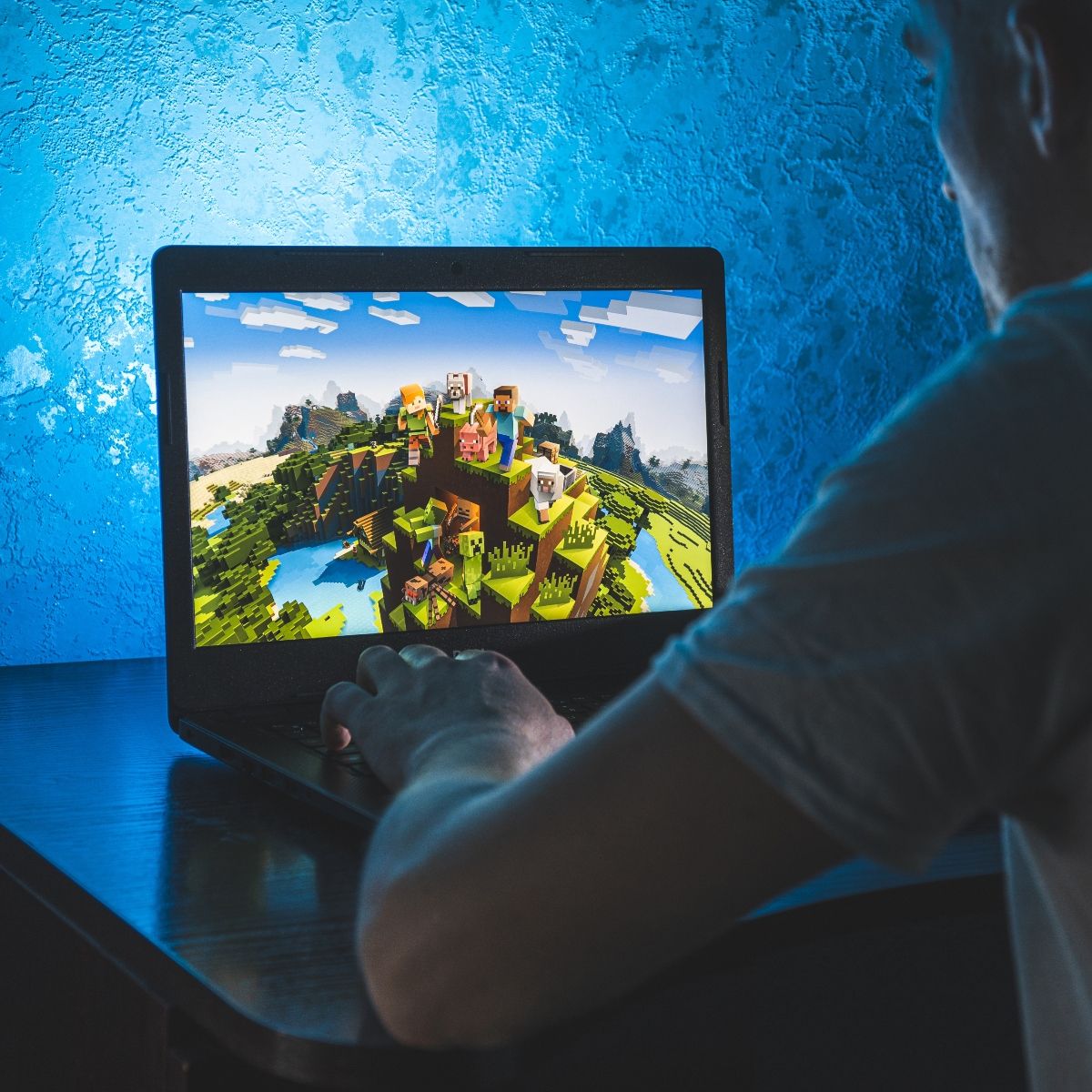 man playing Minecraft on his laptop computer