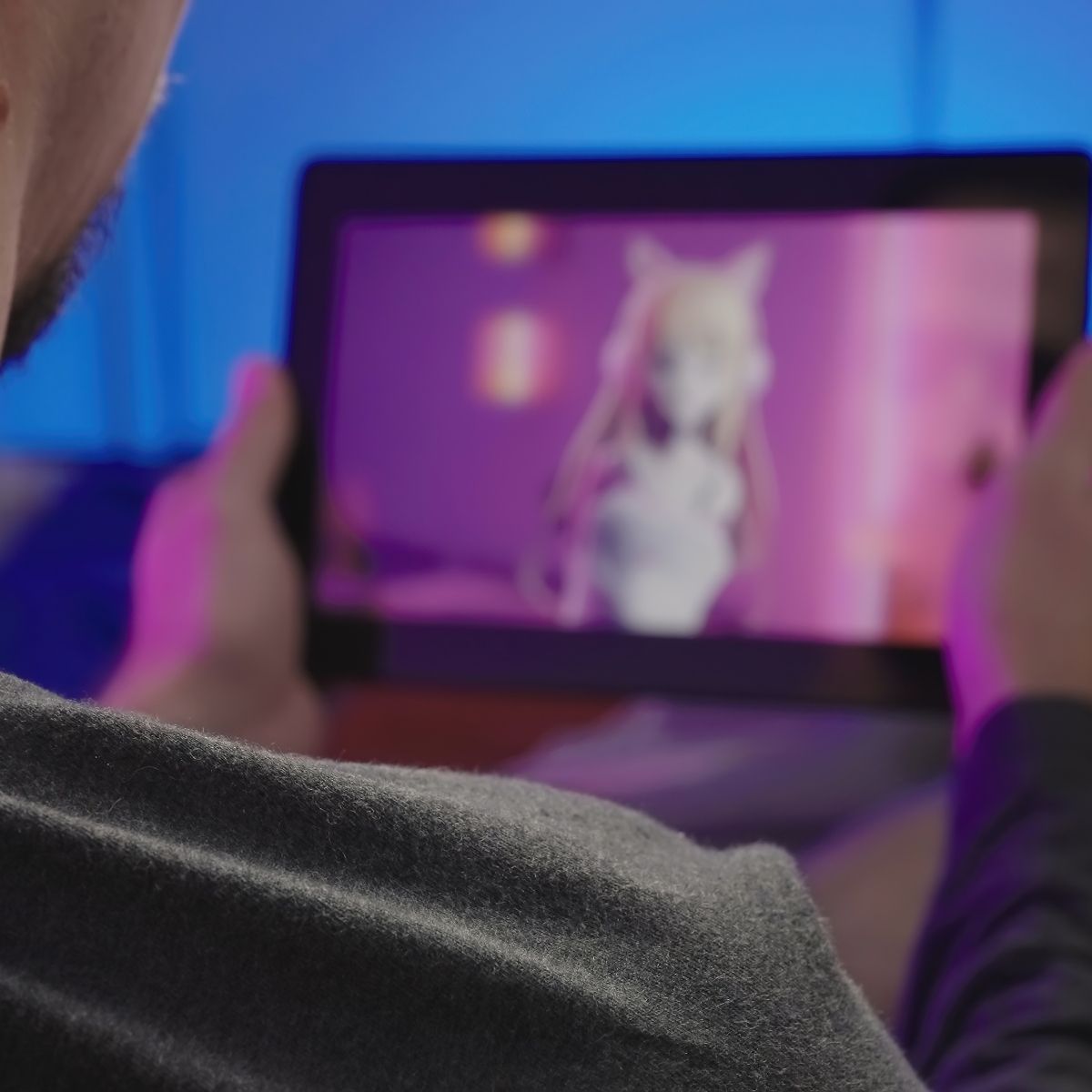 Man holding tablet with a blurred image of a pink anime 