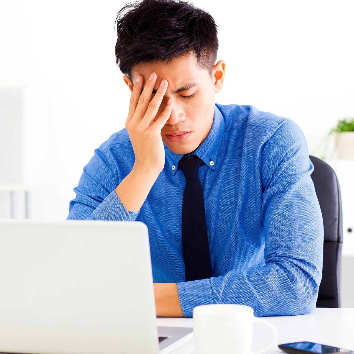Man sitting in front of a laptop looking stressed