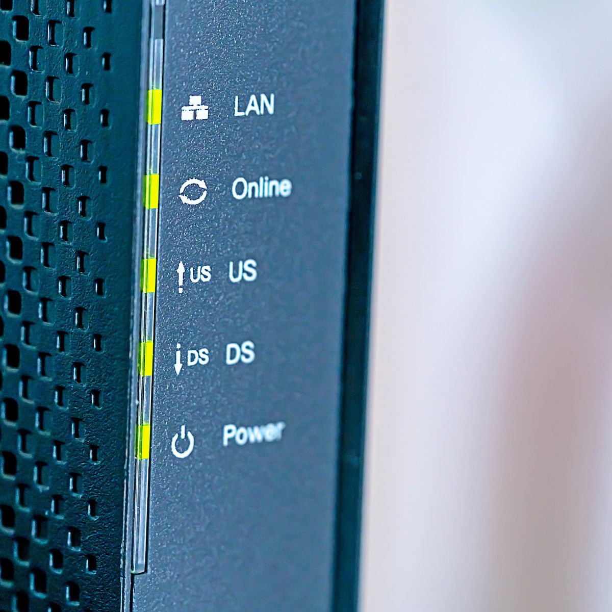 A close-up of the front of a black wireless cable modem/router with green indicator lights.