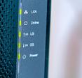 A close-up of the front of a black wireless cable modem/router with green indicator lights.