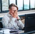 An older white man with light brown hair sits in front of his computer looking frustrated. He&#x27;s just found out his computer has a virus.