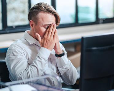 An older white man with light brown hair sits in front of his computer looking frustrated. He&#x27;s just found out his computer has a virus.