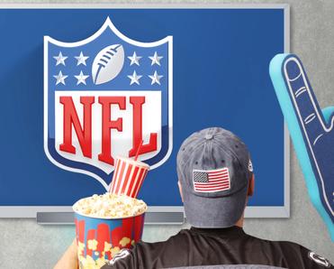 Person&#x27;s back as they wear American flag cap, popcorn and soda on one hand, and a giant foam hand in front of TV that shows NFL 