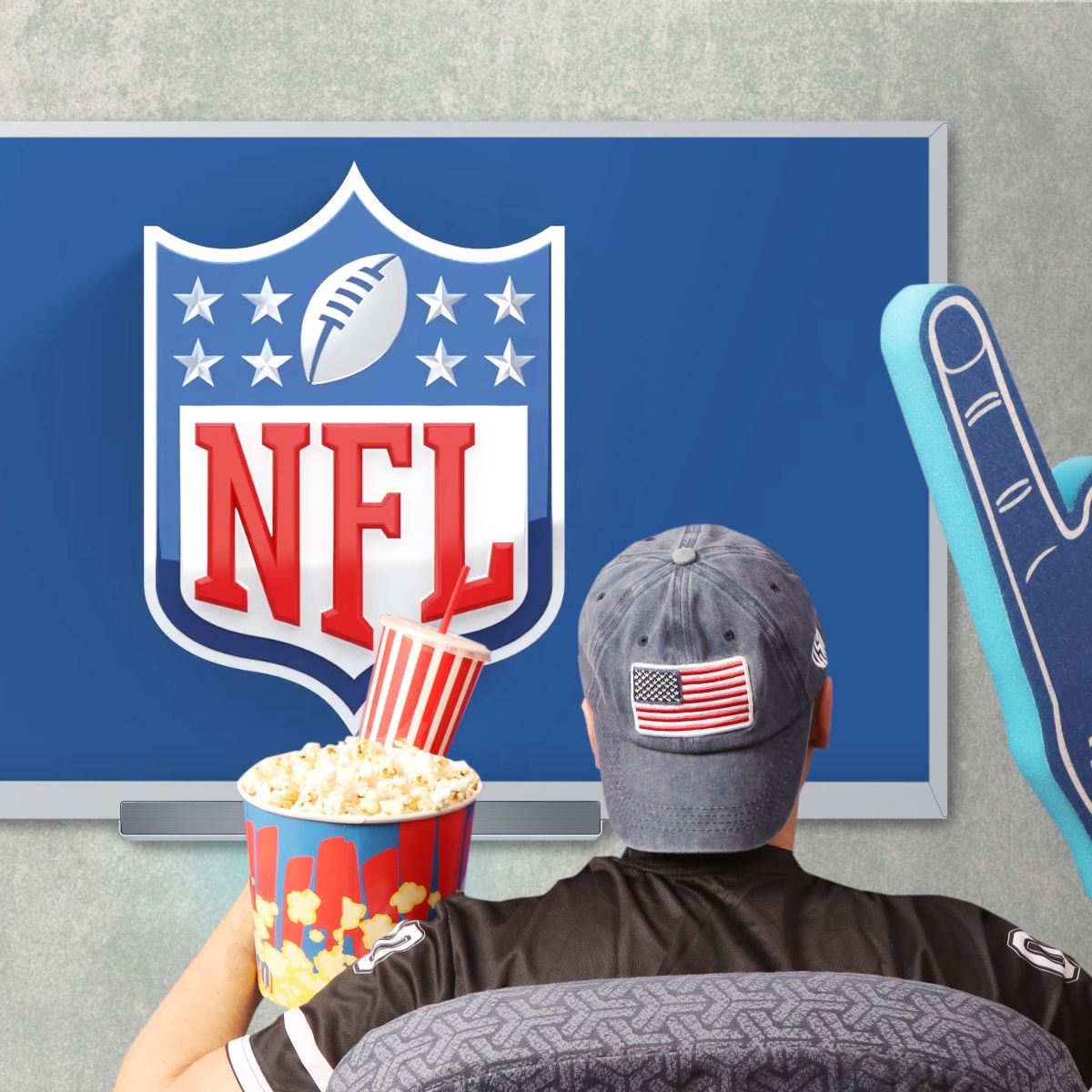 Person&#x27;s back as they wear American flag cap, popcorn and soda on one hand, and a giant foam hand in front of TV that shows NFL 