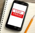 cellphone on top of notebook with yellow pencil on the side, on the screen in red and white &quot;stop fraud&quot; 