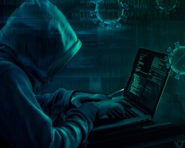 A hooded hacker on their laptop, sending out an online pandemic scam.