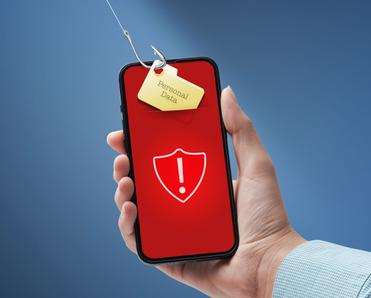 Hand holding phone with with shield and exclamation points on red screen a tag saying &quot;personal data&quot; is under a fishing hook trying to be pulled