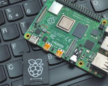 Raspberry Pi device on top of black keyboard with a little raspberry drawing on a key