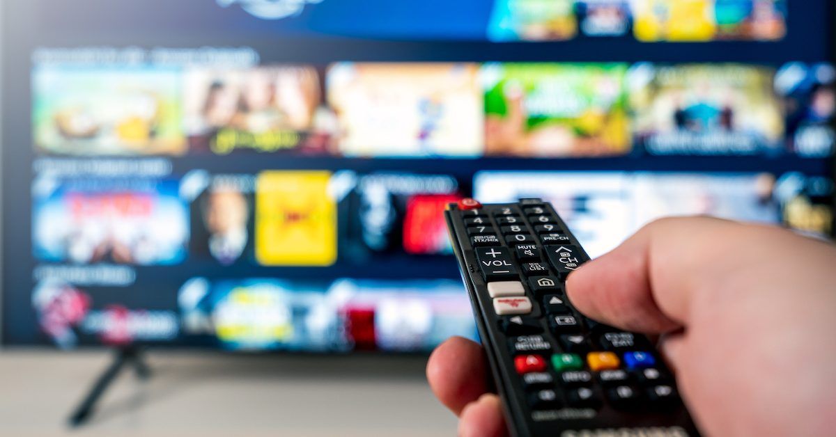 A hand shown holding a remote that&#x27;s pointed at a TV. 